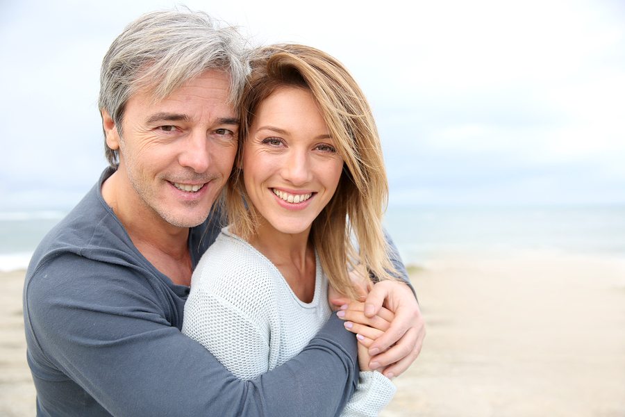 Cheerful mature couple embracing by the beach